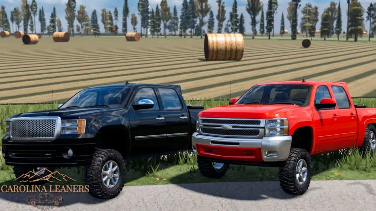 A black and a red lifted pickup side by side at the edge of a mowed hay field.